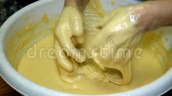 女面包师用手在厨房的一个大碗里大力揉面团视频的预览图