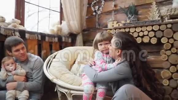妈妈抱着小女儿和家人坐在壁炉旁视频的预览图