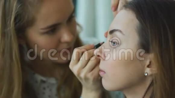 年轻的化妆师在一个重要的活动前为一个女孩做漂亮的化妆让她的眼睛闭上视频的预览图