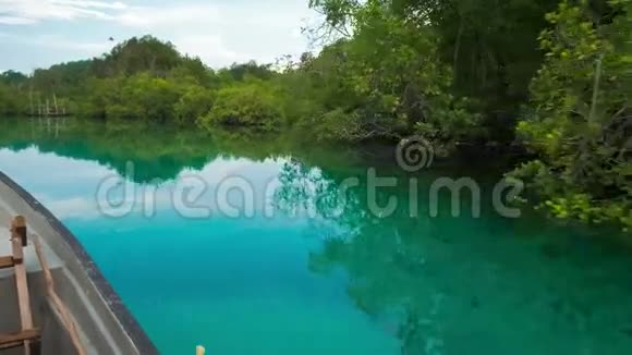 印度尼西亚西巴布亚拉贾安帕特隐湾小船在蓝色浅水处移动平静水面上有红树林倒影视频的预览图