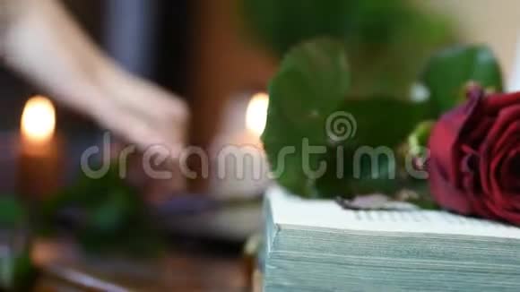 在桌子上拿起一朵红玫瑰上面放着书和蜡烛视频的预览图
