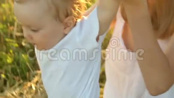 穿着白色衬衫的孩子坐在干草堆附近的年轻母亲穿着白色连衣裙视频的预览图