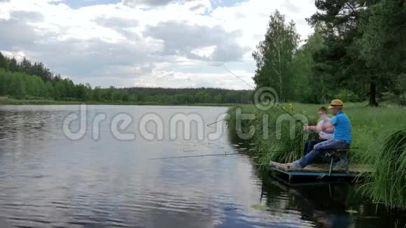 爸爸教儿子在河的长凳上钓鱼视频的预览图