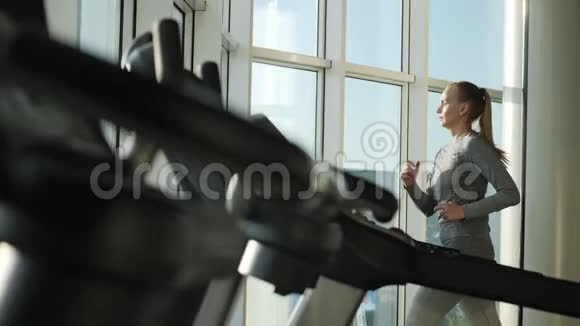 有魅力的中年妇女正在体育健身中心的跑步机上跑步视频的预览图