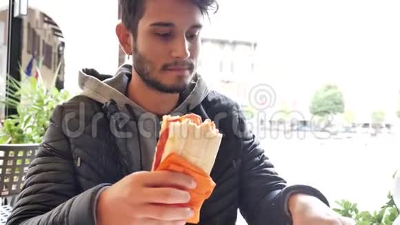 坐在咖啡馆里拿着三明治的年轻人视频的预览图