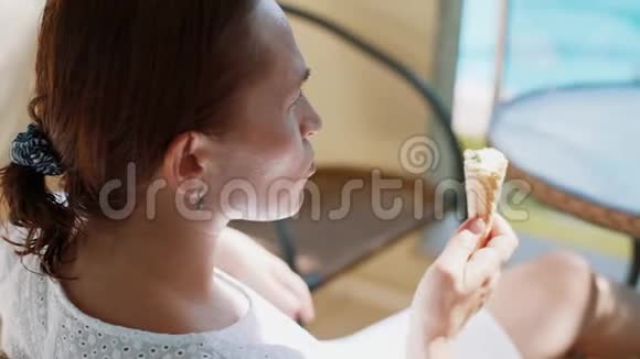 女人一边吃冰淇淋一边坐在阳台上的桌子上视频的预览图