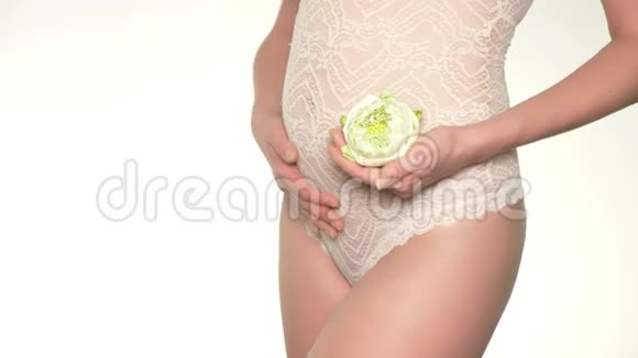 一个孕妇抱着一朵白莲花在她肚子旁边的特写镜头视频的预览图