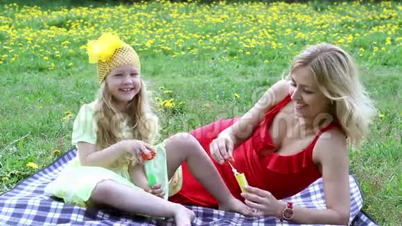 美丽的女人和女孩在户外吹泡泡躺在草地上视频的预览图