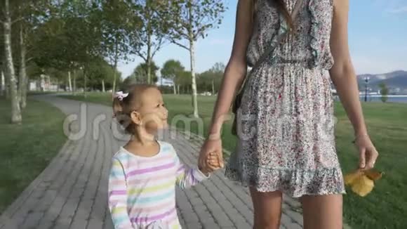 早晨的夏日公园女人和一个漂亮的小女孩牵着手视频的预览图