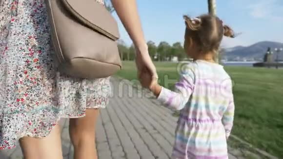 早晨的夏日公园女人和一个漂亮的小女孩牵着手视频的预览图