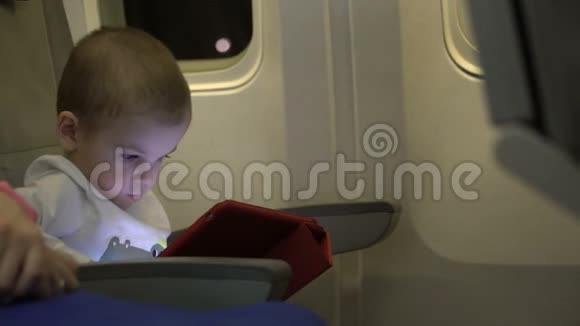 两岁的男孩在平板电脑上玩坐在飞机座位上视频的预览图