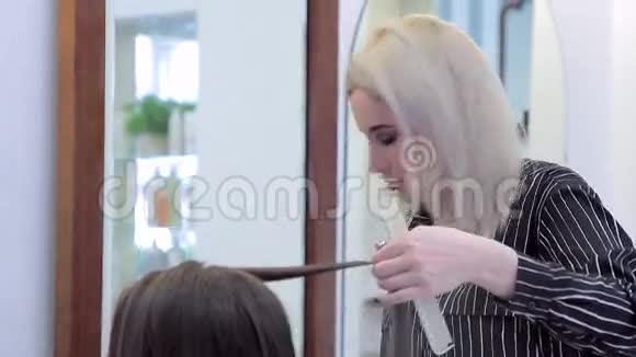 美发师在处理黑发时的特写视频的预览图