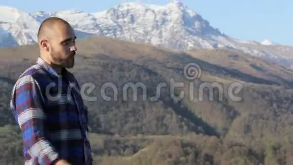 英俊的秃头远足者在大自然中在美丽的山景中吃面包视频的预览图