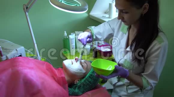 一个年轻的女孩在一个接待与美容师美容师把面具戴在脸上视频的预览图