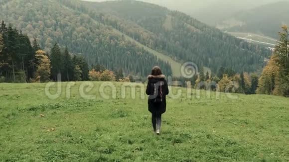 镜头跟随年轻女孩徒步旅行者走在户外的背景山区景观视频的预览图