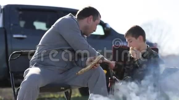 父子俩在篝火旁吃烤面包喝汽水视频的预览图