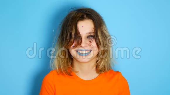 一个留着长发的快乐女孩笑着双手捧着她的脸站在室内被隔绝在蓝色之外视频的预览图