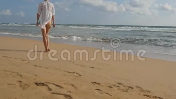 穿着泳衣和衬衫的漂亮女人赤脚在海边散步去海边的小女孩女性脚视频的预览图
