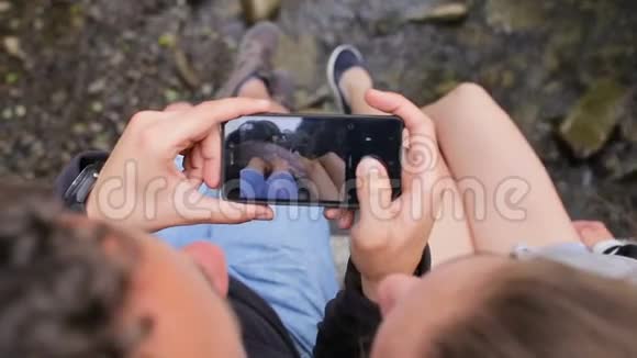 年轻的一对游客背着背包在一座山河上的桥上在的背景上拍一张脚的照片视频的预览图