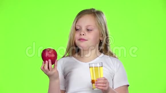 小女孩从杯子里喝果汁拿着苹果绿色屏幕慢动作视频的预览图
