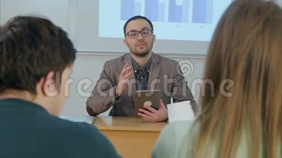 男老师拿着平板电脑坐在教室前面视频的预览图
