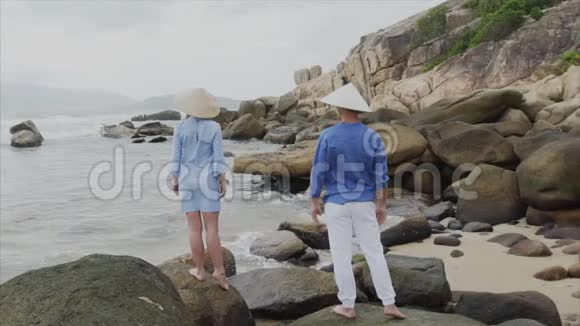 一男一女戴着越南帽子站在海边互相伸出双手一种概念视频的预览图