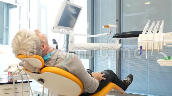 一位年轻英俊的男子坐在牙医的椅子上他转过身来微笑着对着镜头竖起大拇指视频的预览图