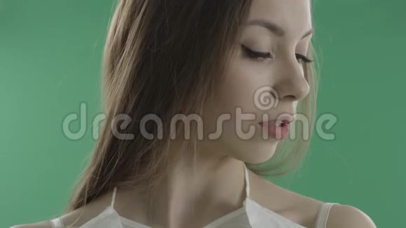 漂亮的年轻女子在绿色的背景下咬着嘴唇视频的预览图
