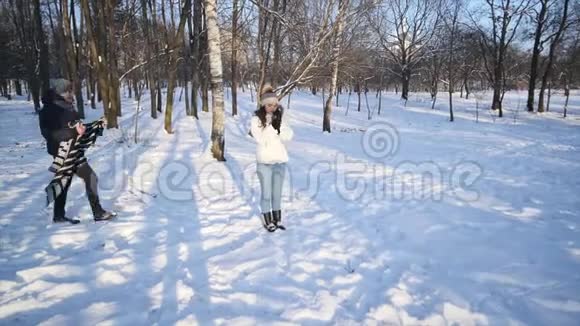 可爱的一对情侣在一个下雪的公园里有爱心的年轻人用毯子把他的女朋友盖住视频的预览图
