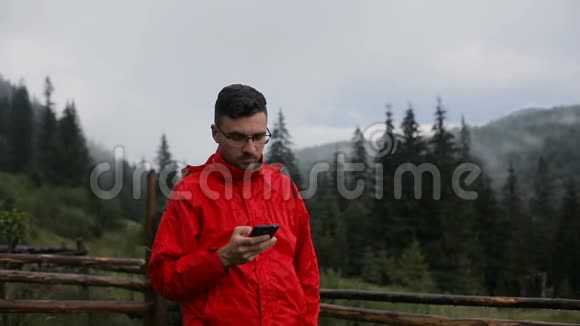 一个年轻人晚上在山上写短信在雾中的森林周围视频的预览图