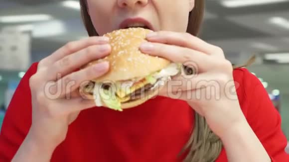 饥饿的女孩在食物场上吃汉堡包快餐店的女人咬芝士汉堡视频的预览图