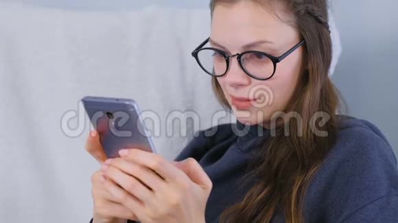 戴眼镜的年轻黑发女人在手机上输入信息视频的预览图