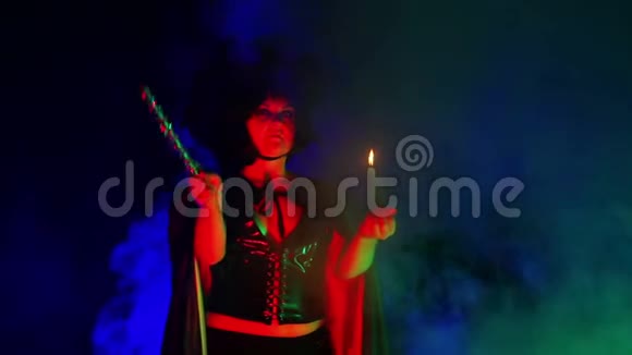 一个穿着黑色烟云手里拿着蜡烛的年轻女巫正在从事魔法视频的预览图