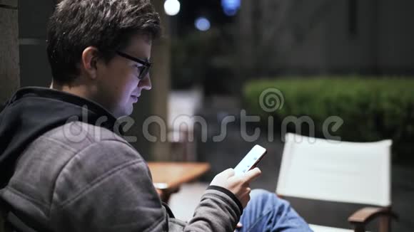 一个年轻人在夜街上网的侧景视频的预览图
