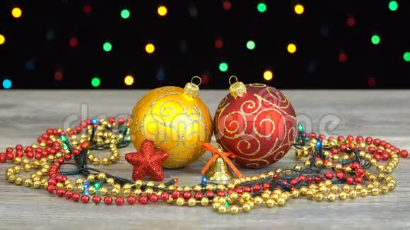 美丽的圣诞节红色和金色的球和装饰在木地板上的彩色闪光花环上的黑色视频的预览图