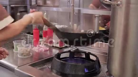 咖啡馆的厨师用一个平底锅把蔬菜搅拌在炉火上视频的预览图