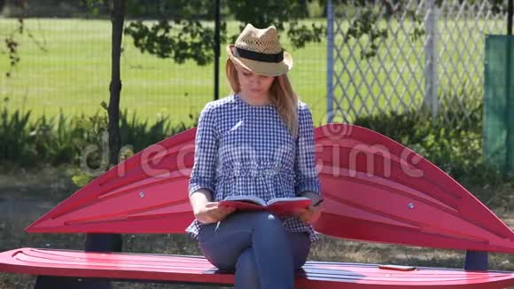 美丽的金发女郎在长凳上的公园里的相册里画了一支铅笔视频的预览图