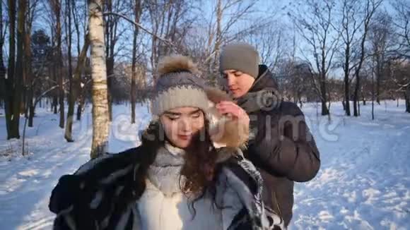 可爱的一对情侣在一个下雪的公园里有爱心的年轻人用毯子把他的女朋友盖住视频的预览图