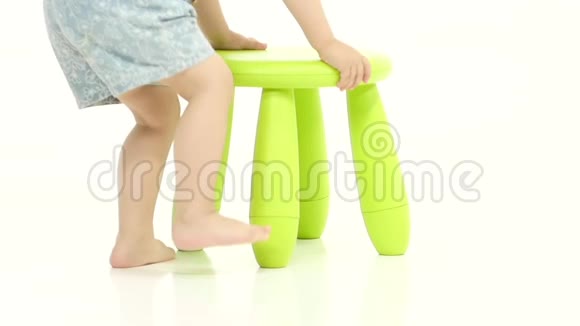 婴儿坐在绿色的椅子上拿着一颗糖果白色背景慢动作视频的预览图