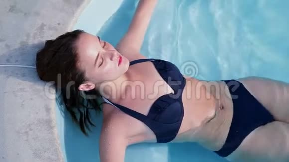 年轻女子躺在游泳池里放松视频的预览图