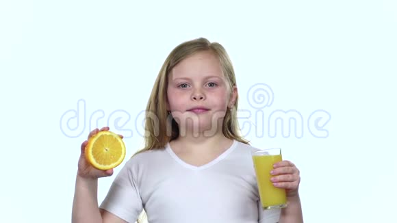 小女孩拿着一块橘子片舔它喝橙汁白色背景慢动作视频的预览图