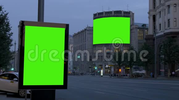两块绿色屏风的大广告牌晚上在一条繁忙的街道上视频的预览图
