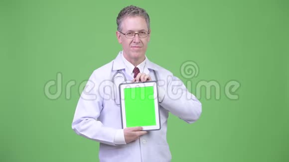 快乐成熟男医生的画像显示数字平板电脑视频的预览图