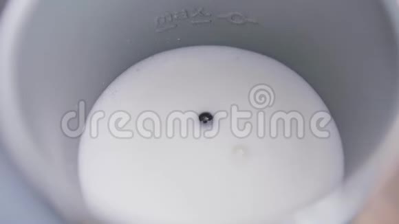 牛奶在金属电动牛奶泡沫中摇动底部有小缕缕视频的预览图