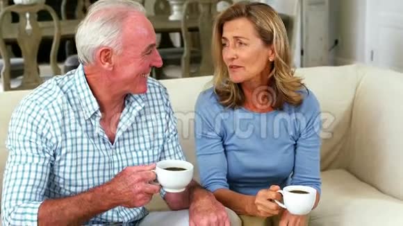 在客厅喝杯咖啡时微笑的老夫妇在互动视频的预览图