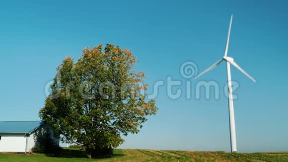 房屋或农场的独立供电风力发电机在建筑物附近一棵树正在附近生长视频的预览图