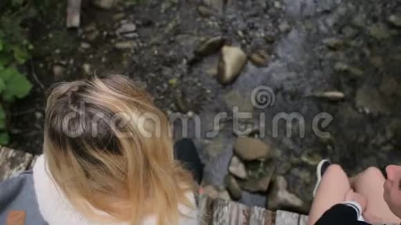 年轻女孩坐在横跨山河的桥上视频的预览图