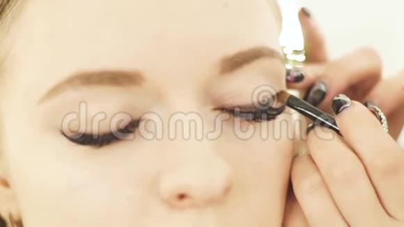 女人用化妆品刷妆眼睛美容模特为美丽的女人做化妆的眼睛视频的预览图