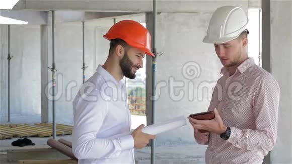 两位建筑工人正在施工的大楼里看着数码平板电脑视频的预览图