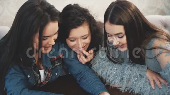 三个朋友坐在一家带着智能手机的咖啡馆里进行着有趣的谈话漂亮的女孩长着漂亮的黑色视频的预览图